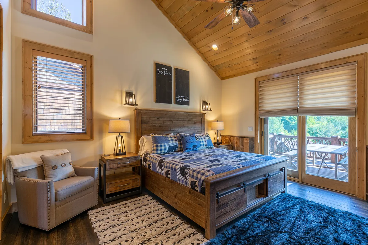 A tranquil bedroom scene with ample windows that offer views outside, a comfortable bed, and a seating area. The natural light and scenic glimpses reinforce the connection to the outdoors, inviting restful moments after day-long adventures.